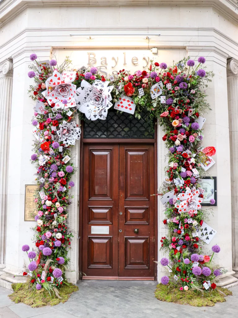 A grand wooden doorway with a floral arch crafted from playing cards