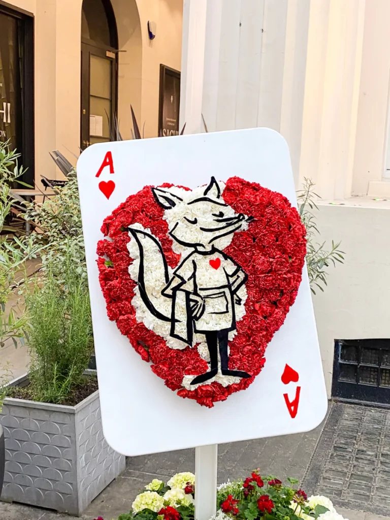 A playing card with a heart made of flowers with a cartoon fox in the middle