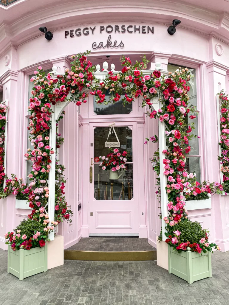 a pink cupcake shop with a floral arch made of roses