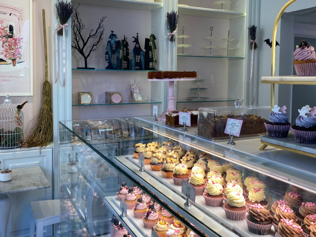 the inside of Peggy Porschen Belgravia. A cake counter with lots  of different cupcakes in the window