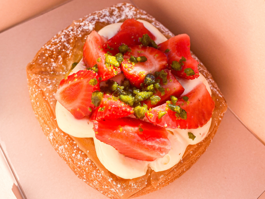 Pastry with elderflower cream, strawberries, and pistachios on