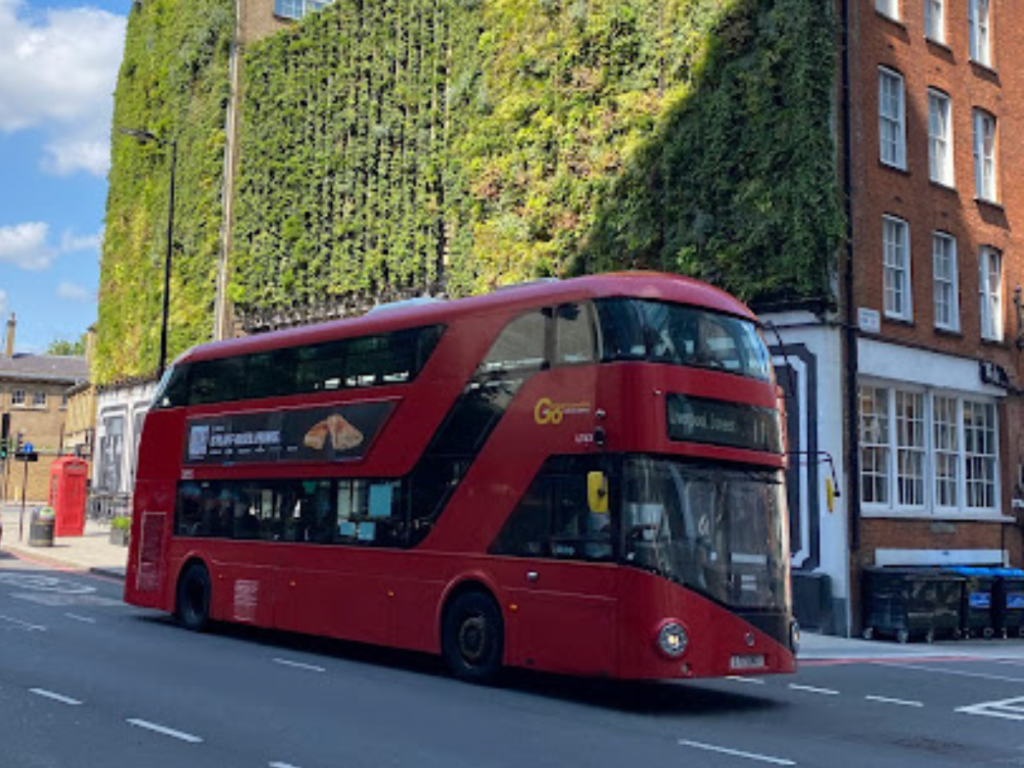 Red London bus in front of greenery wall in Victoria