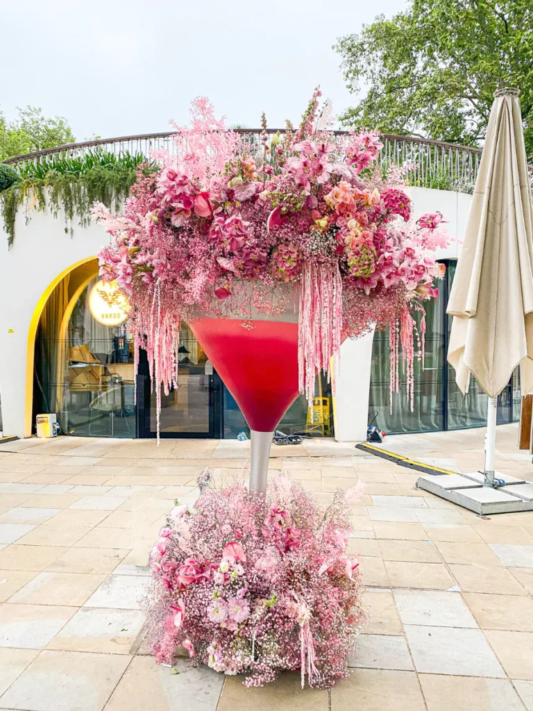 A large martini glass filled with fluffy pink flowers brimming over the edges outside Vardo in Chelsea