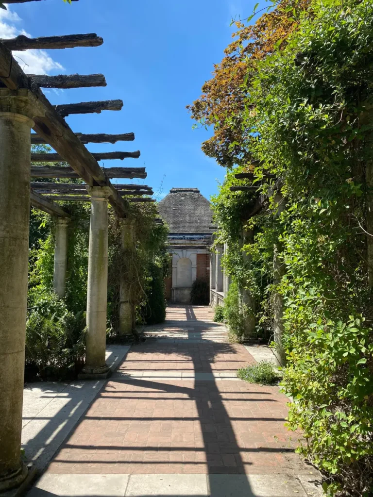 Greenery on one side and a pergola on the other