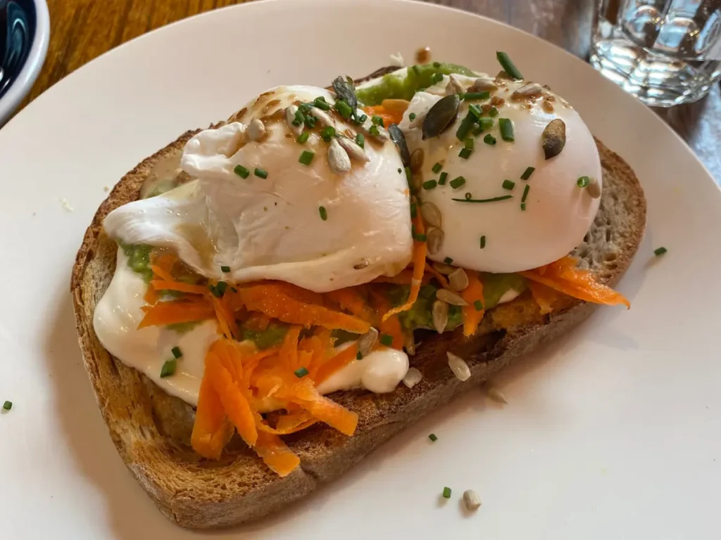 Sourdough toast with grated carrot and two poached eggs